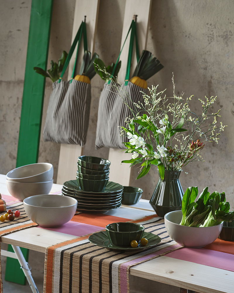 Una mesa de madera en una habitación de estilo industrial está dispuesta con varios elementos de mesa de la colección MÄVINN.