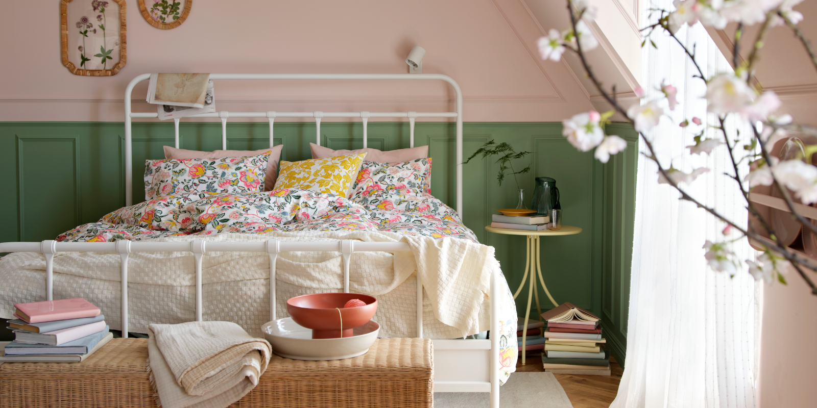 Un dormitorio luminoso con un armazón de cama STJÄRNÖ blanco adornado con un colorido juego de funda nórdica y fundas de almohada DAGGSALVIA.