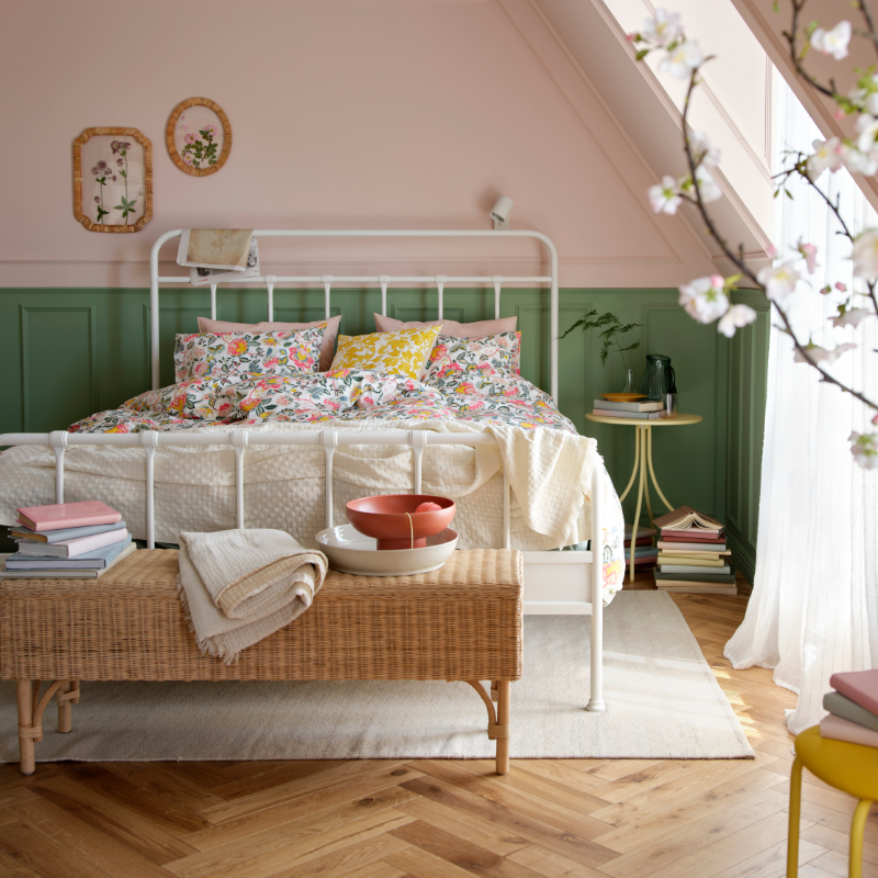 Un dormitorio luminoso con un armazón de cama STJÄRNÖ blanco adornado con un colorido juego de funda nórdica y fundas de almohada DAGGSALVIA.