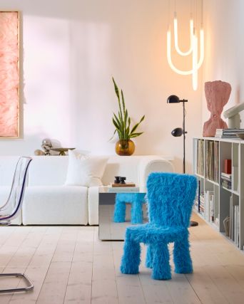 A child’s chair in a GRESIMOJS chair cover in blue faux fur is in a bright and modern living room, by a mirrored side table.