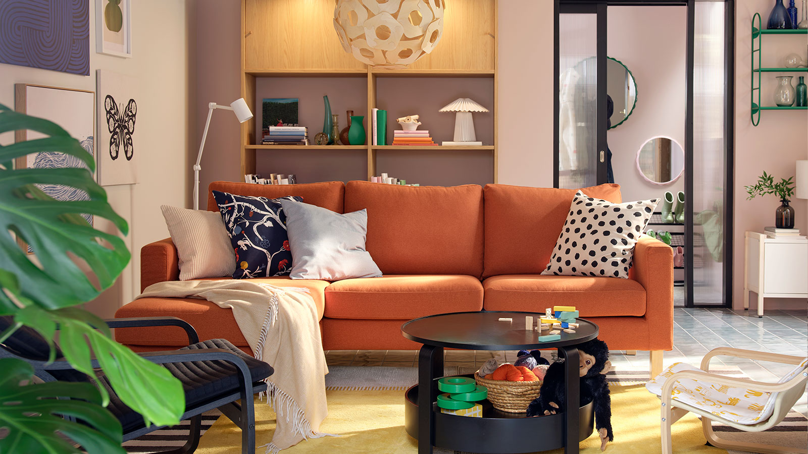Una luminosa sala de estar con un sofá de tres plazas SALTSJÖBADEN de color marrón rojizo flanqueado por sillones, una mesa de centro y juguetes.
