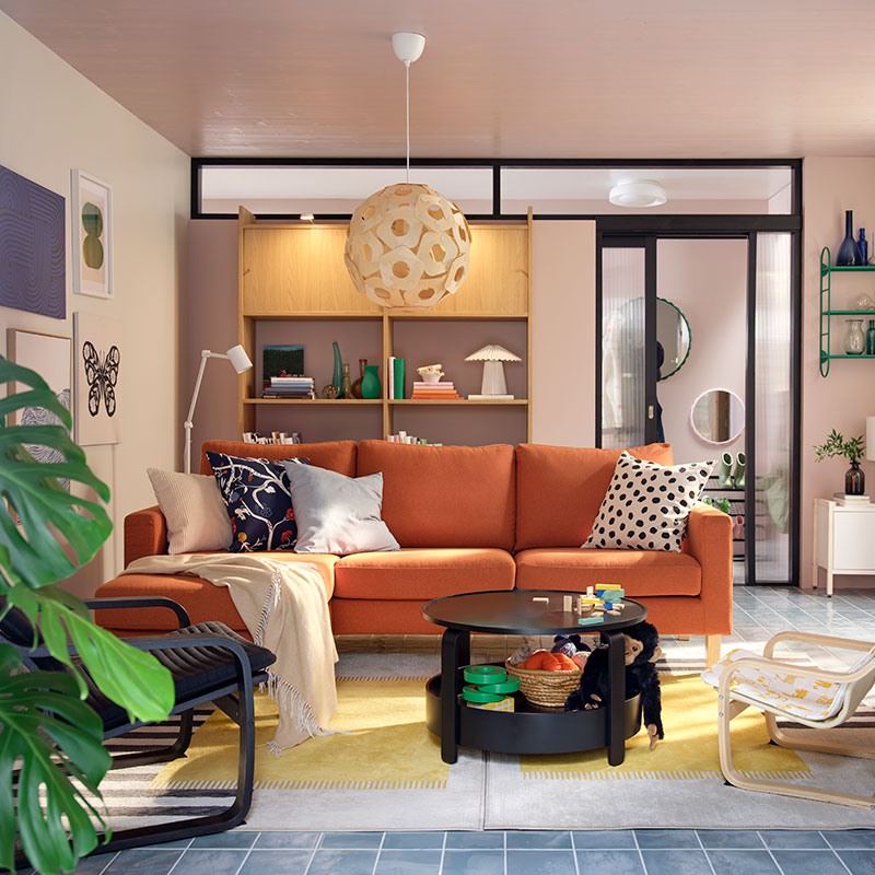 Una luminosa sala de estar con un sofá de tres plazas SALTSJÖBADEN de color marrón rojizo flanqueado por sillones, una mesa de centro y juguetes.