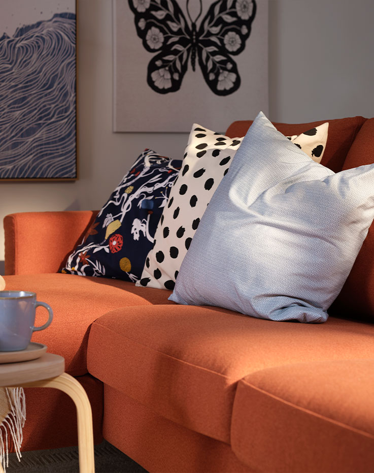 Una sala de estar con un sofá de tres plazas SALTSJÖBADEN de color marrón rojizo con chaise longue, complementado con cojines decorativos.