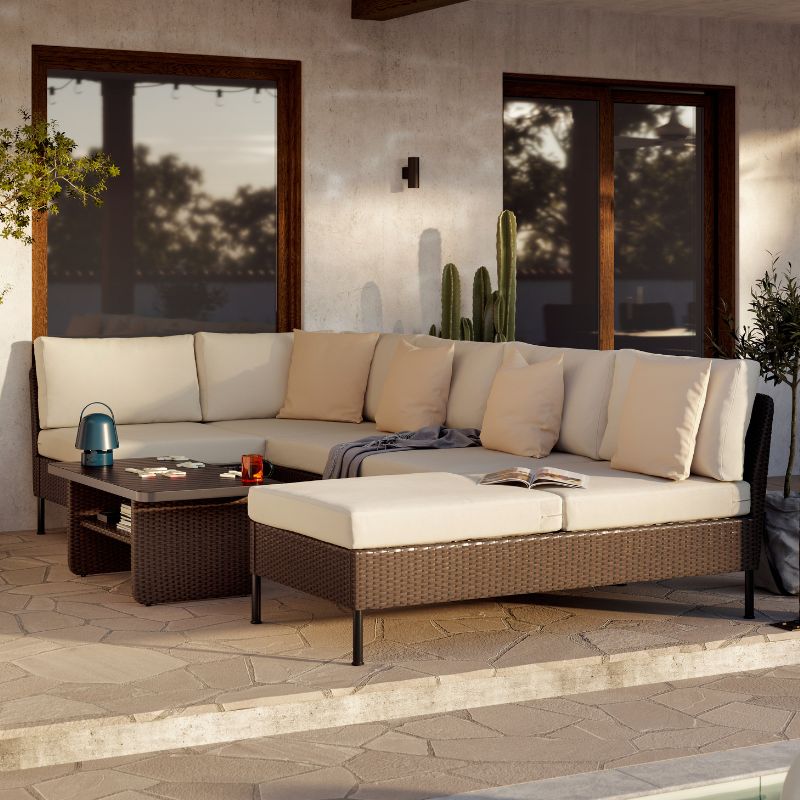 Bajo el sol de la tarde, un sofá modular VITTSKÄR de color beige con cojines y una manta HOLMVI gris, una mesa de centro gris oscuro.