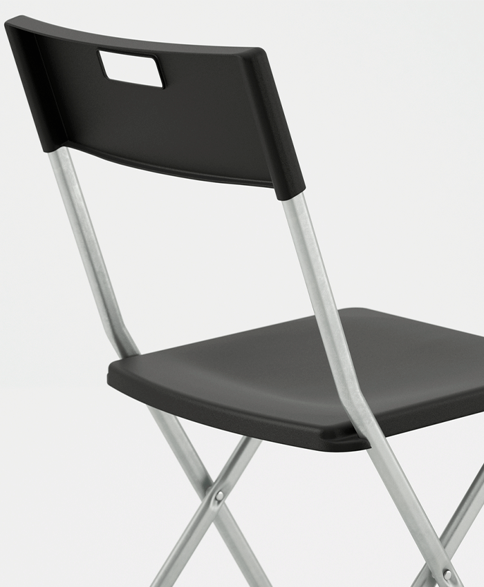Close-up of a black folding chair showing the plastic seat and backrest with a built-in handle, supported by a sturdy silver metal frame.