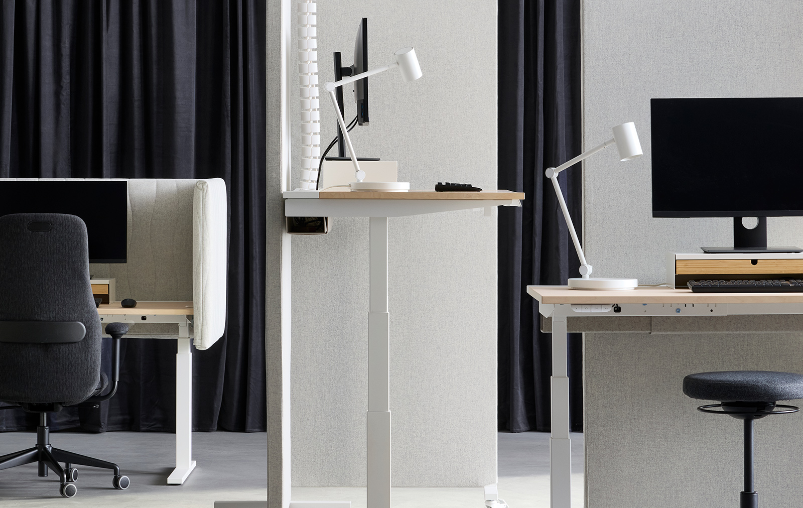 Office space with sit/stand desk workstations, separated by beige-white MITTZON acoustic screens in Gunnared fabric.