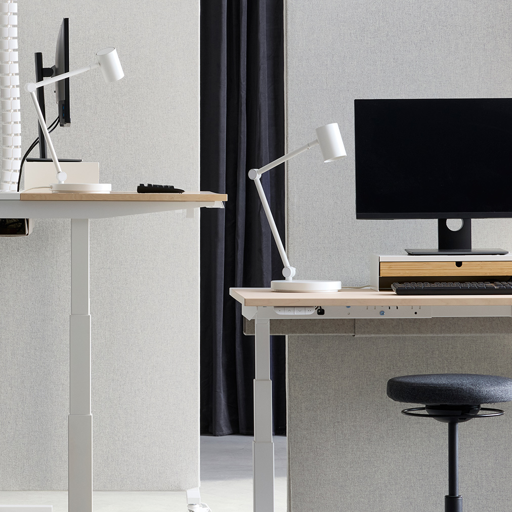 Office space with sit/stand desk workstations, separated by beige-white MITTZON acoustic screens in Gunnared fabric.