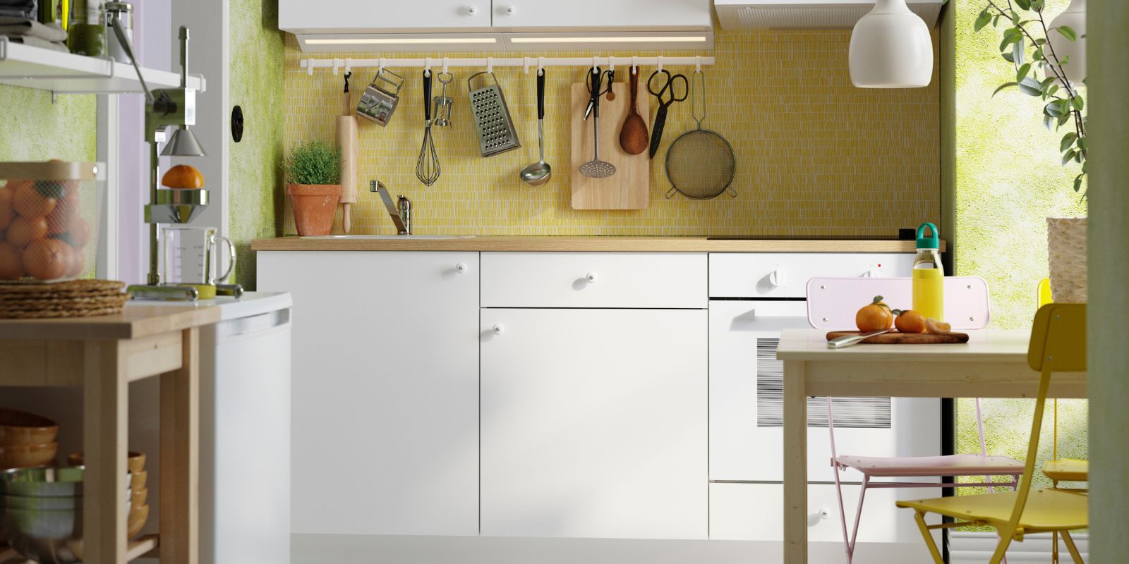 Cocina luminosa y compacta con gabinetes blancos, salpicadero amarillo, luz natural y utensilios y plantas colgantes.