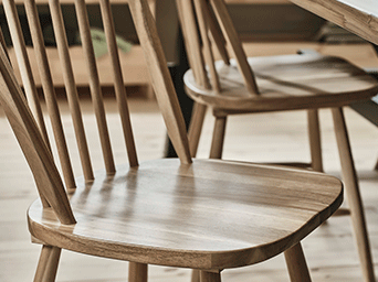 Detailed view of a classic spindle-back wooden chair showing the smooth finish of the seat and the fine vertical bars of the backrest.