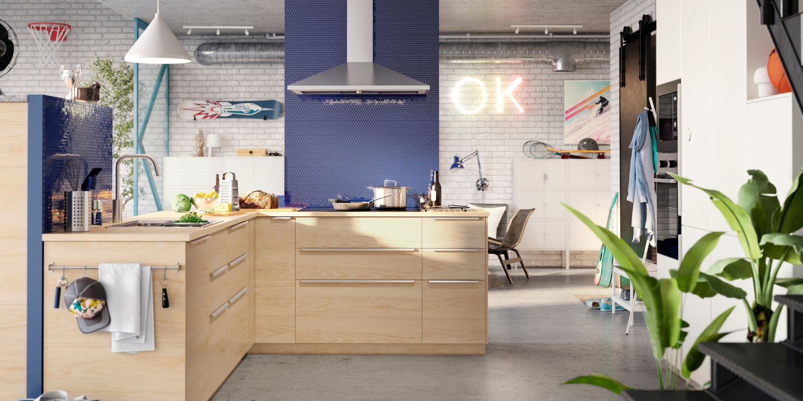 Cocina moderna con gabinetes de madera clara, pared azul, isla central y campana extractora metálica. Ladrillos blancos y letrero "OK" iluminado.