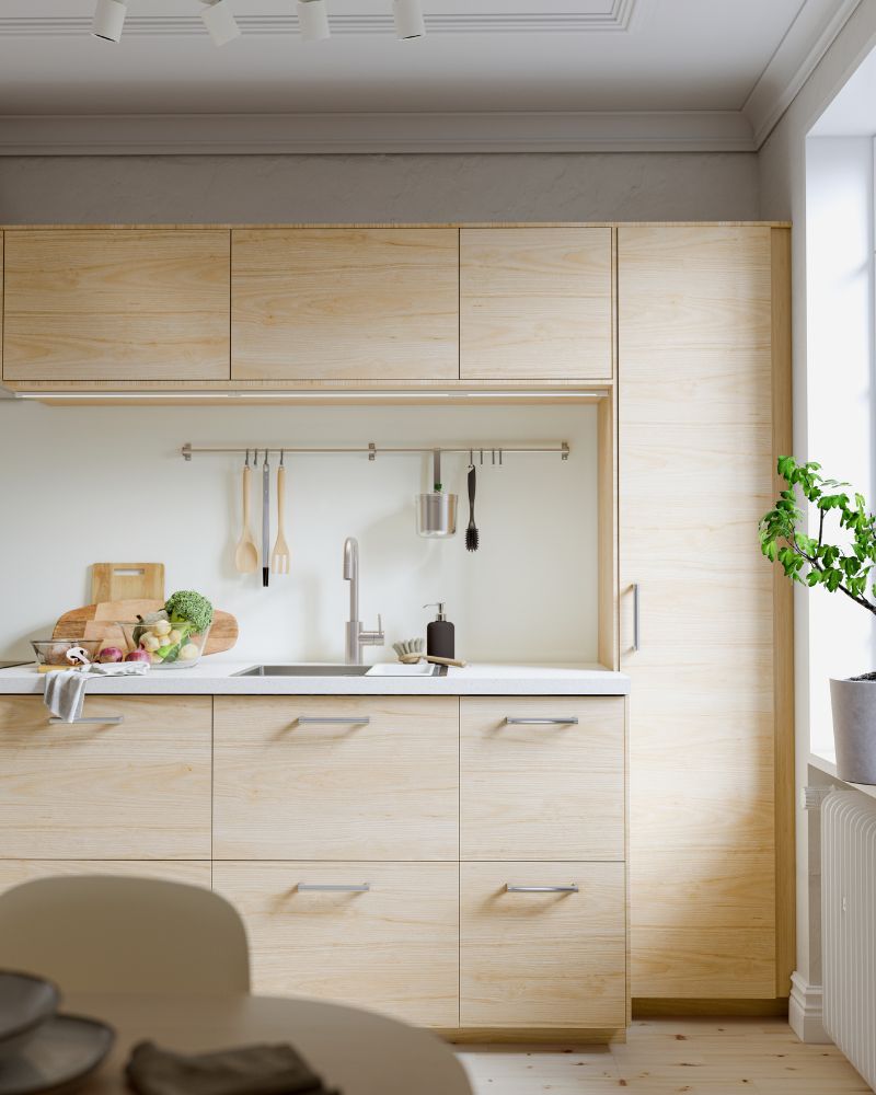 Cocina luminosa con gabinetes de madera clara, encimera y salpicadero de mármol blanco. Estantes abiertos con vajilla.