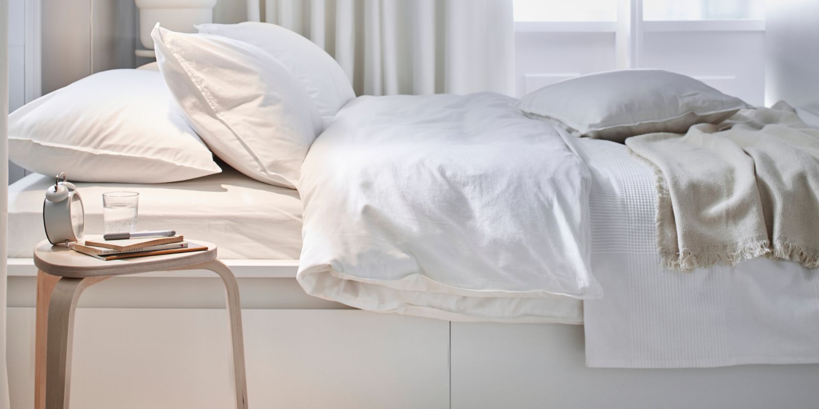 Cama MALM con funda ÄNGSLILJA, manta GUNNEMOR, taburete KYRRE y cortinas MERETE en un espacio luminoso y sereno.