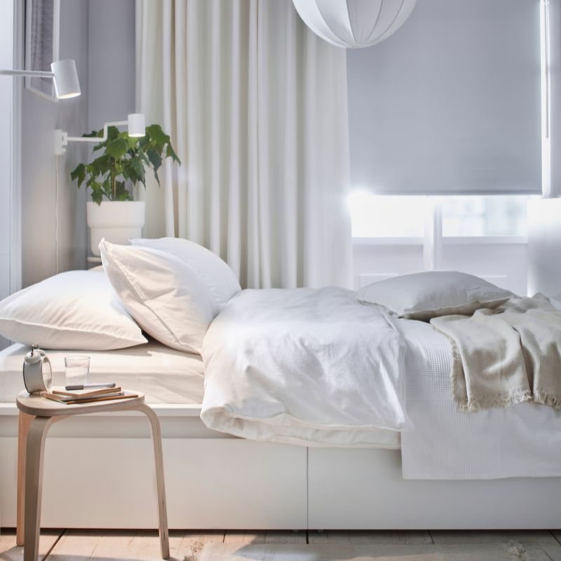Cama MALM con funda ÄNGSLILJA, manta GUNNEMOR, taburete KYRRE y cortinas MERETE en un espacio luminoso y sereno.