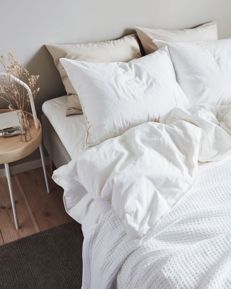 ÄNGSLILJA viste la cama con suavidad, acompañada de la mesa auxiliar BURVIK y la alfombra STOENSE, creando un dormitorio sereno y acogedor.
