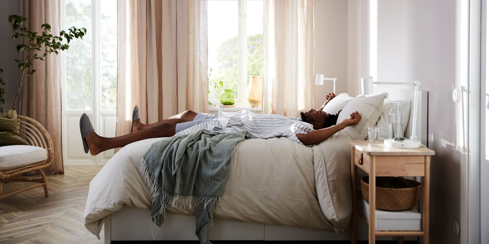 Dormitorio luminoso con cama MALM, lámpara NYMÅNE y cortinas HÄLLEBRÄCKA creando un ambiente cálido y relajante.