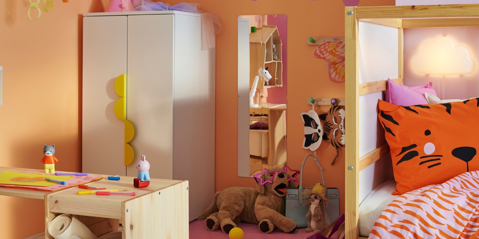 Un marco y un tablero TROFAST de pino teñido en blanco claro forman un escritorio en la habitación de un niño con un armario SMÅSTAD/PLATSA.