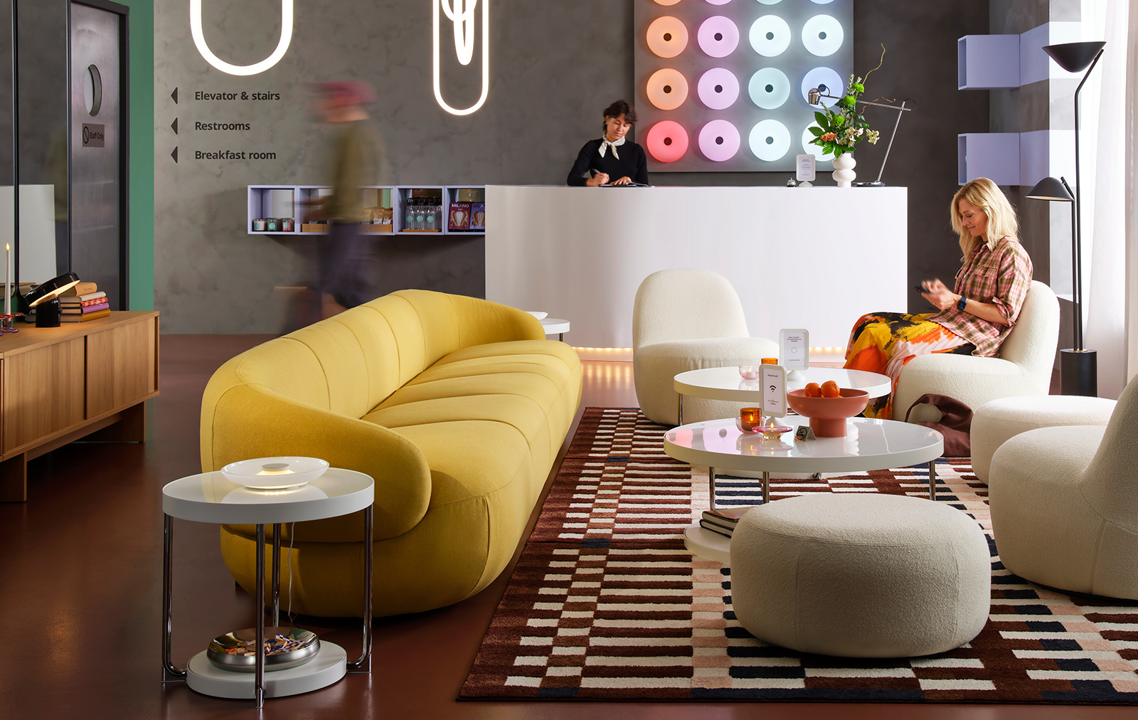 Un sofá LILLESÄTER de 6 plazas en Gunnared verde amarillo brillante ancla una zona de asientos en un salón de hotel moderno con varias personas.