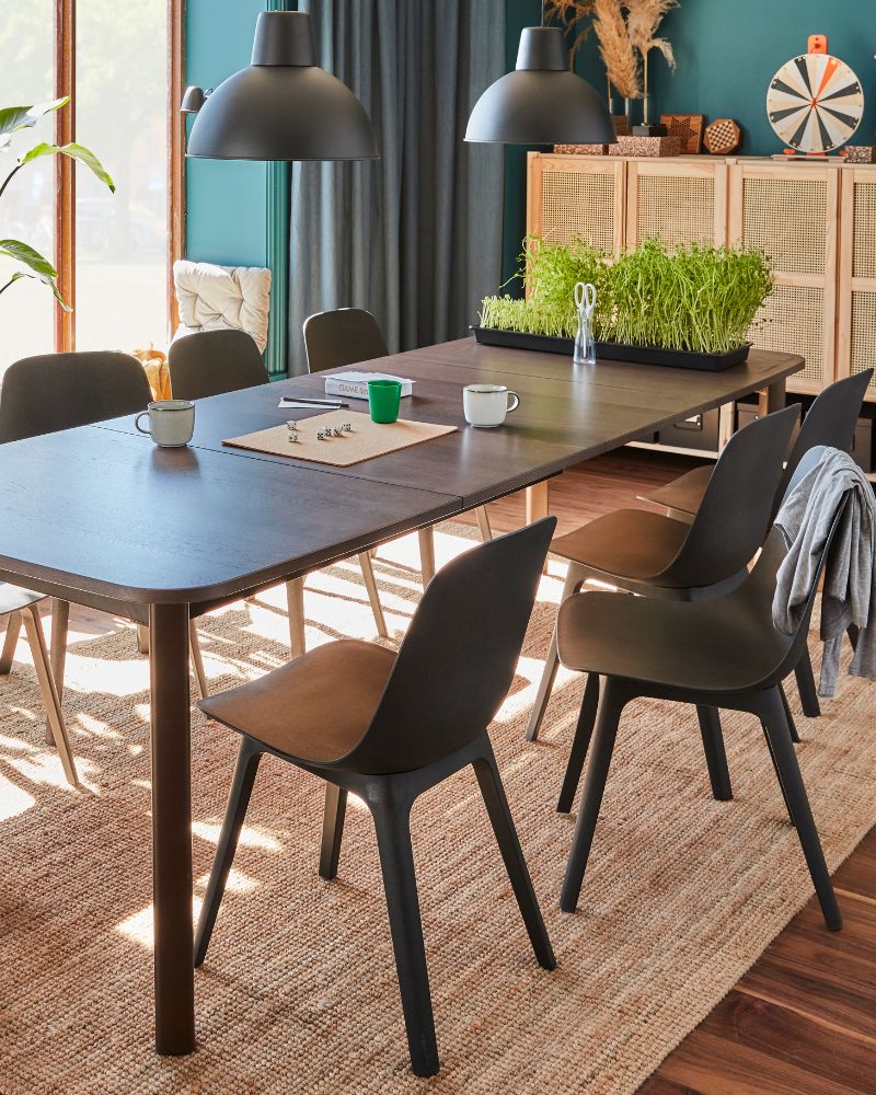 Comedor moderno con mesa STRANDTORP, sillas ODGER, lámparas SKURUP, alfombra LOHALS, cortinas STENFRÖ y estantería IVAR.