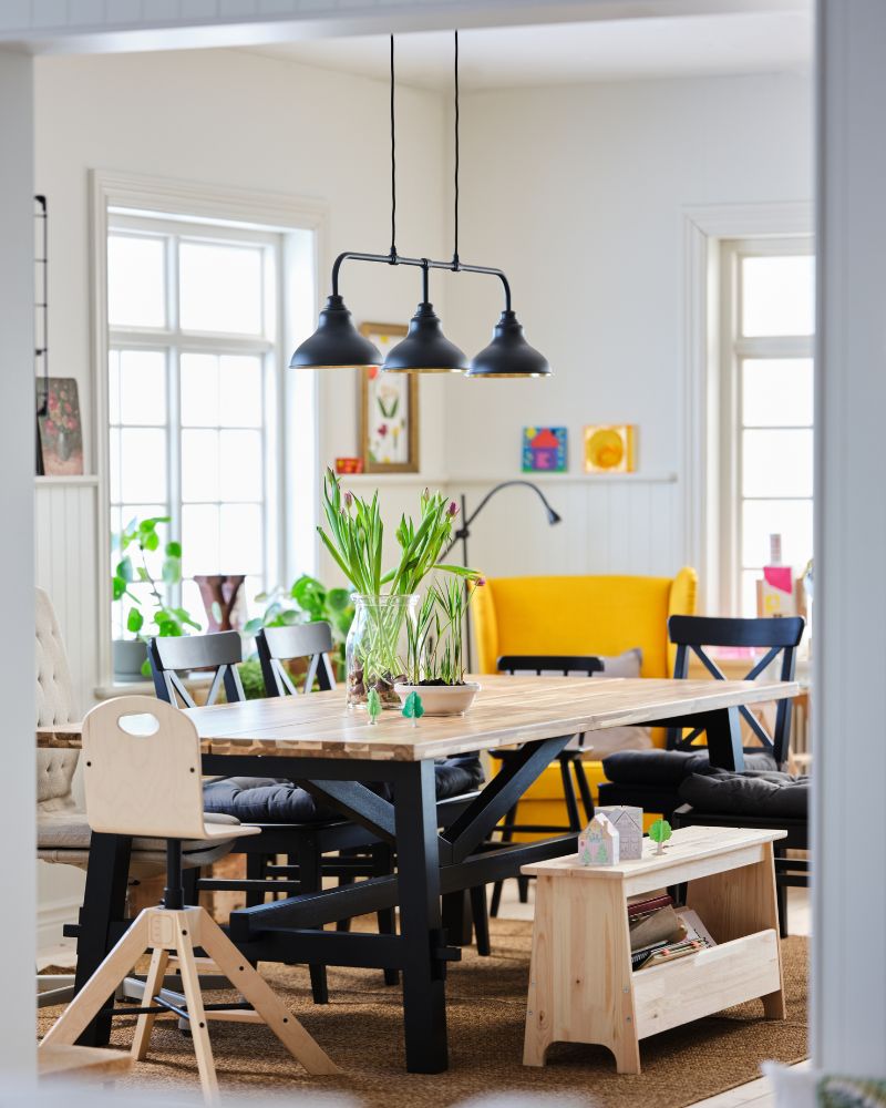 Cozy dining area with SKOGSTA table, ROSENTORP and AGAM chairs, STRANDMON armchairs, AGUNNARYD lamp, LOHALS rug and PERJOHAN bench.