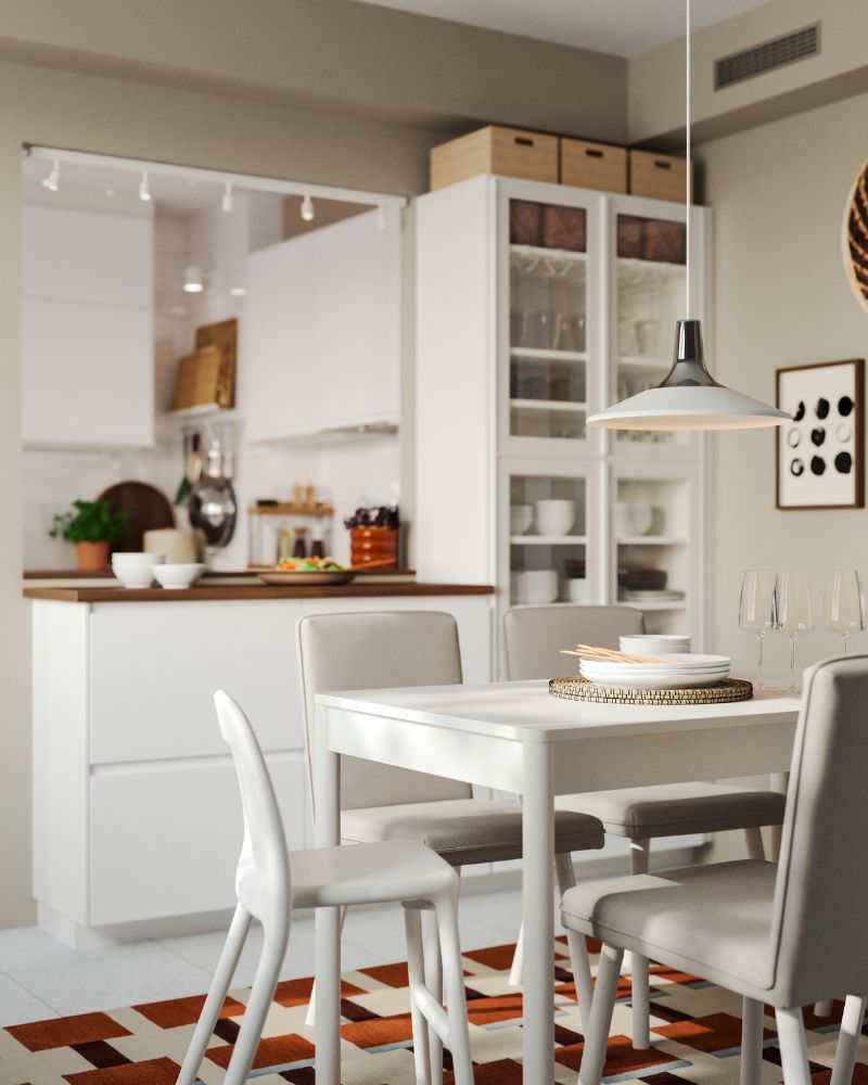 La cocina blanca cuenta con una península fabricada con muebles de cocina METOD y hay una mesa de comedor y sillas blancas.
