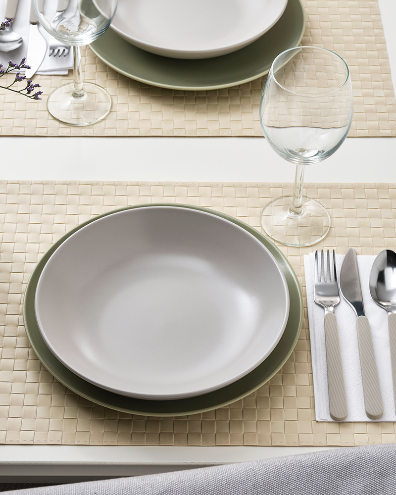 A FÄRGKLAR deep plate on top of a MOSSMAL plate next to a STORSINT wine glass on a dining table.