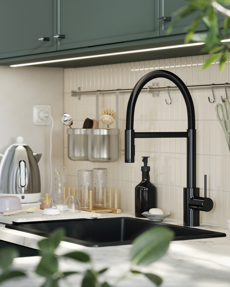 A SALLSJÖN kitchen mixer tap with a gooseneck design is mounted in a kitchen with a tiled wall and grey-green kitchen doors.