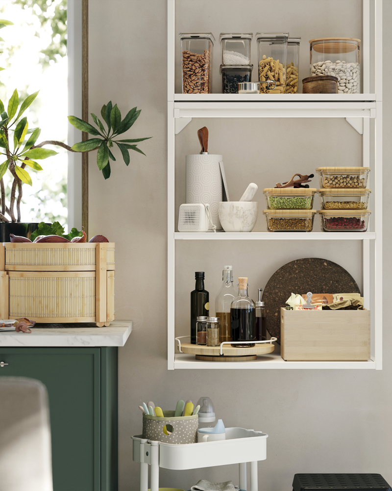 An ENHET wall frame is mounted on a kitchen wall and there’s a basket made of bamboo on the kitchen worktop next to it.