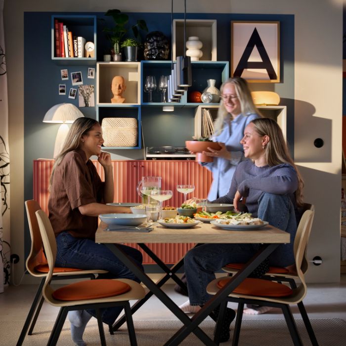 Warm dining room with SKÅLSTA chairs and table, EKET shelves, VINDKRAFT and VARMBLIXT lamps, RÖDALM frame and STORSINT glasses.