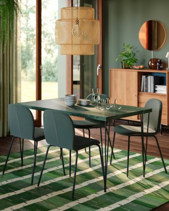 Modern dining room with SKÅLSTA chairs, SKÅLSTA table, SINNERLIG lamp, RÅDMANSÖ cabinets and GLADELIG tableware on a green rug.