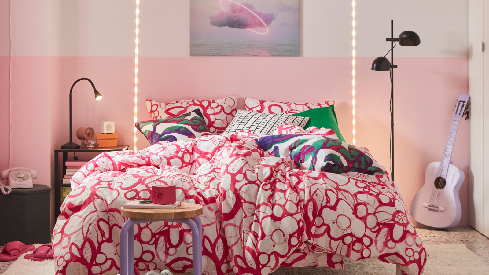 A colourful bedroom features a white and bright pink HÄRLIR duvet cover and pillowcases with a floral pattern on the bed.