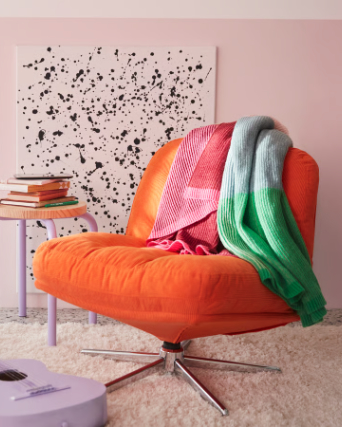 A bedroom with a pink/green ÄLVSJÖSKOGEN cushion cover placed on a green GURLI cushion cover stacked on a stool.
