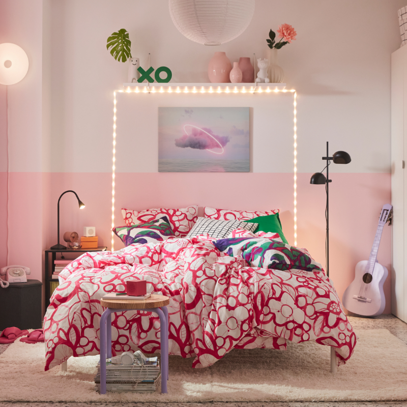 A colourful bedroom features a white and bright pink HÄRLIR duvet cover and pillowcases with a floral pattern on the bed.