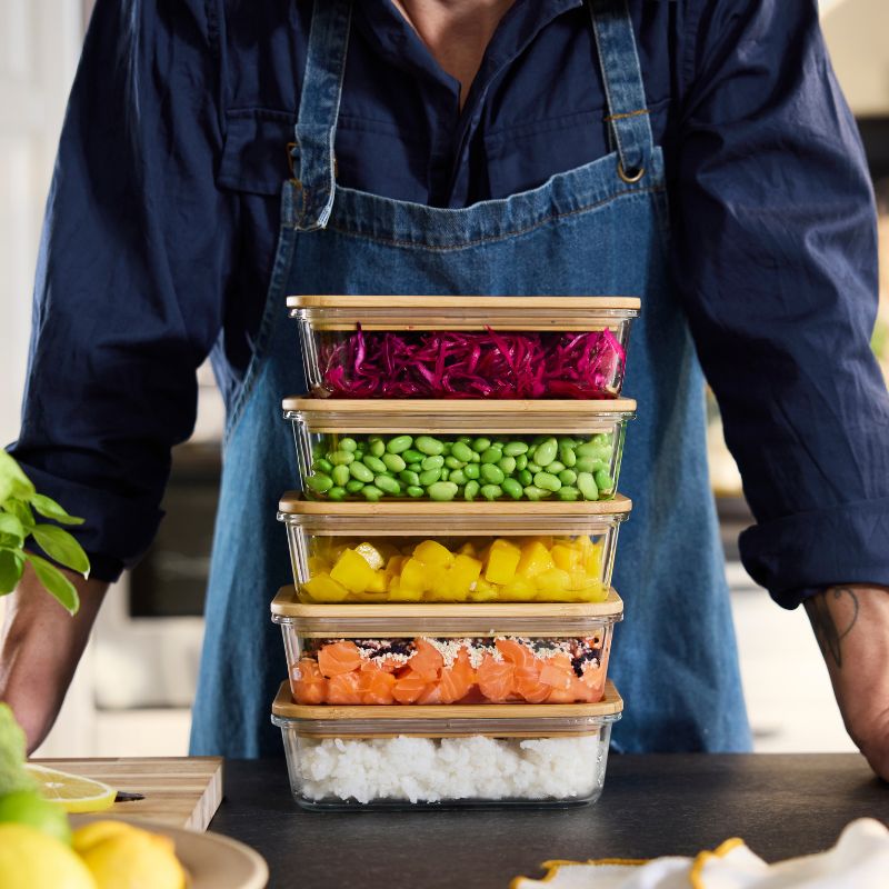 Preparación de cocina vibrante con recipientes con tapa IKEA 365+, envases transparentes apilados con vegetales picados y coloridos.