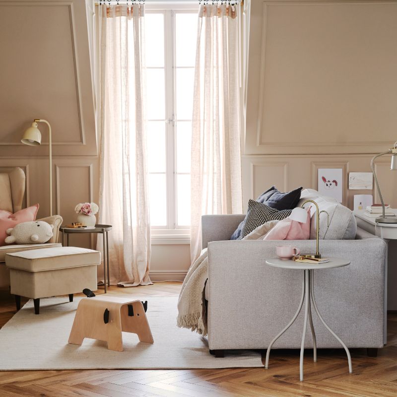An EKHOLMA 2-seat sofa-bed stands in a multipurpose living room opposite a STRANDMON wing chair with footstool.