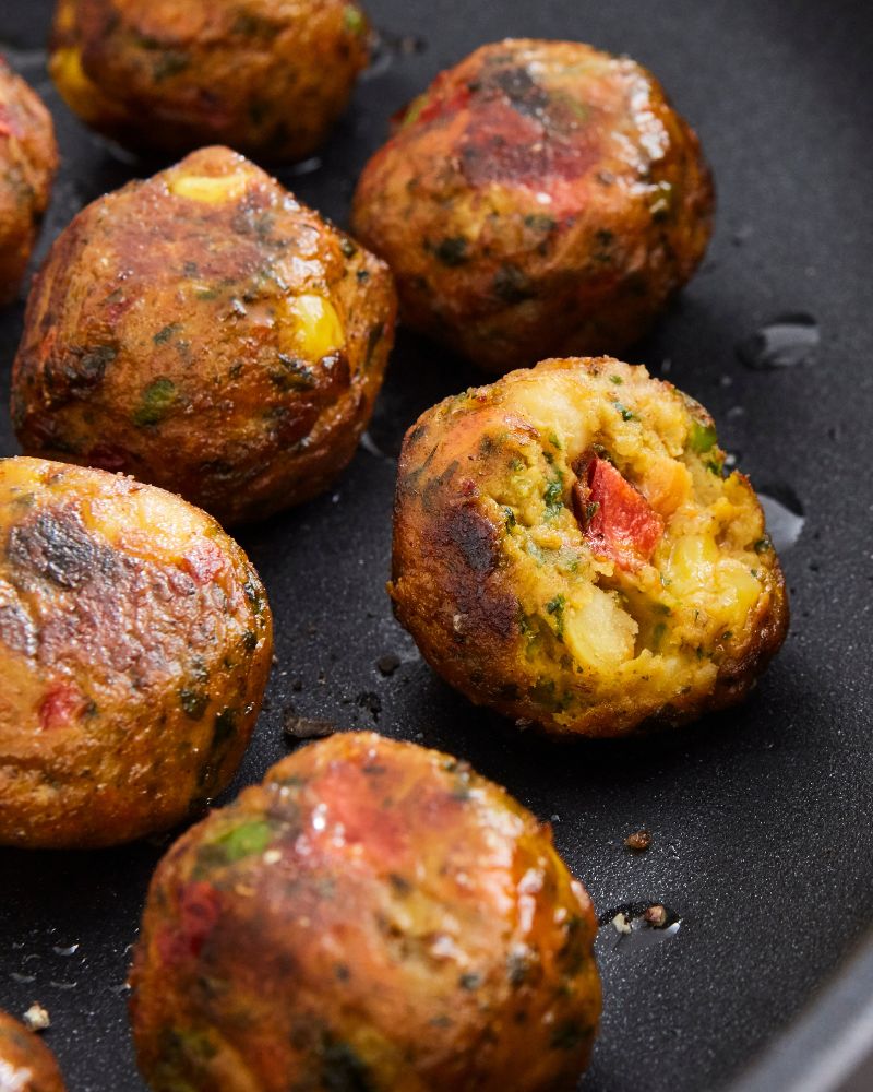 Primer plano culinario y rústico con sartén HEMLAGAD y albóndigas de verduras HUVUDROLL, doradas y listas. 