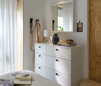 Bright bedroom with white dresser, mirror, and bedside decor