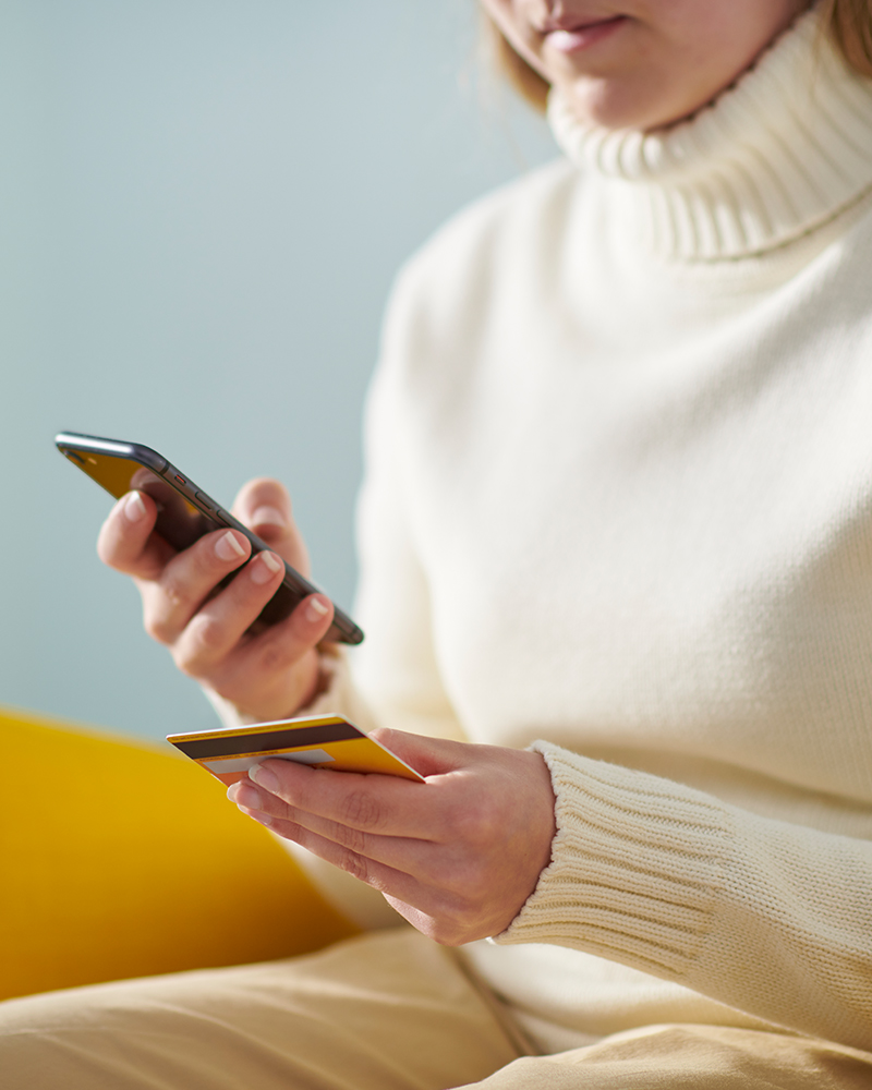 Mujer insertando datos de la tarjeta en el móvil para compra online.