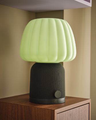 Modern green table lamp on a wooden cabinet.