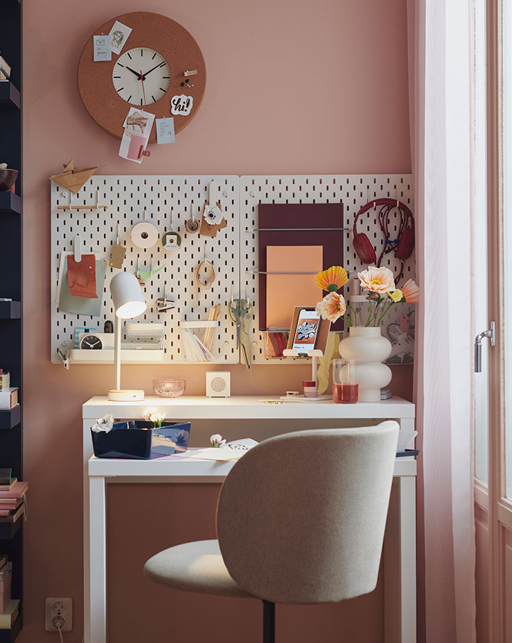 A KRYLBO swivel chair stands at a desk. On the wall above are SKÅDIS pegboards and a SVARTGÖK wall clock.