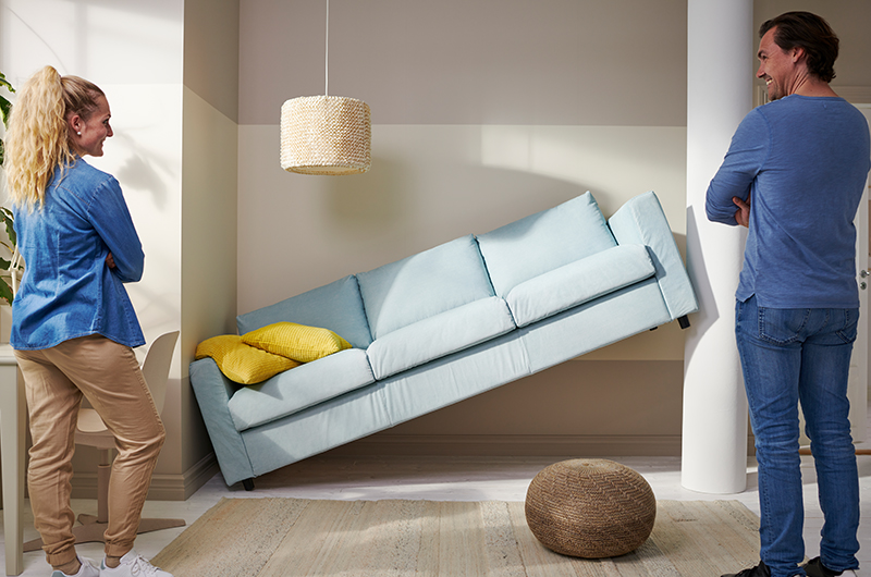 Two people placing a sofa.