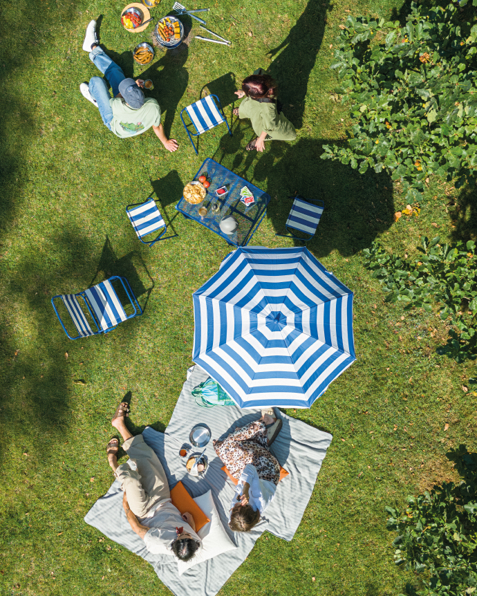 Garden picnic with blanket, umbrella, and small table seen from above.