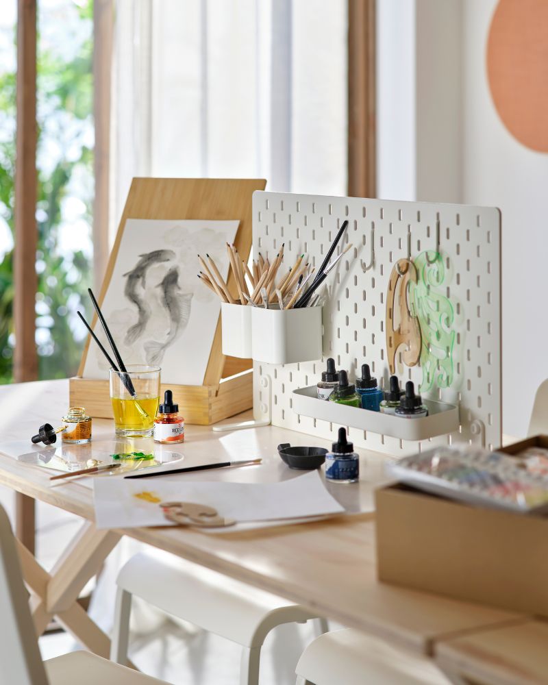 Espacio creativo de oficina con mesa IKEA PS 2026, silla TEODORES, tablero SKÅDIS, caballetes SOLFÅGEL y bocinas SOLSKYDD.