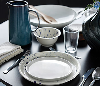 An IKEA 365+ side plate stands on a SILVERSIDA plate near a SILVERSIDA bowl and a blue GLADELIG jug on a table.