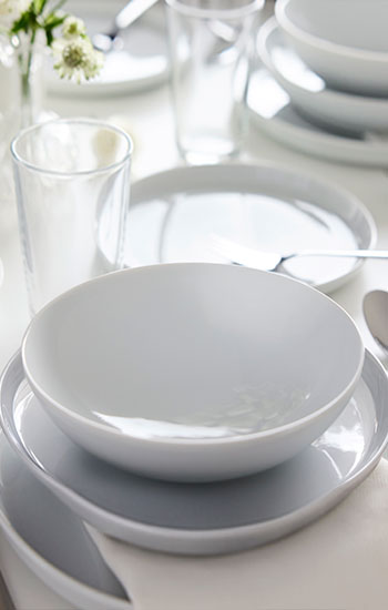 A place setting with a white IKEA 365+ bowl on top of a white IKEA 365+ side plate on top of a white IKEA 365+ plate.