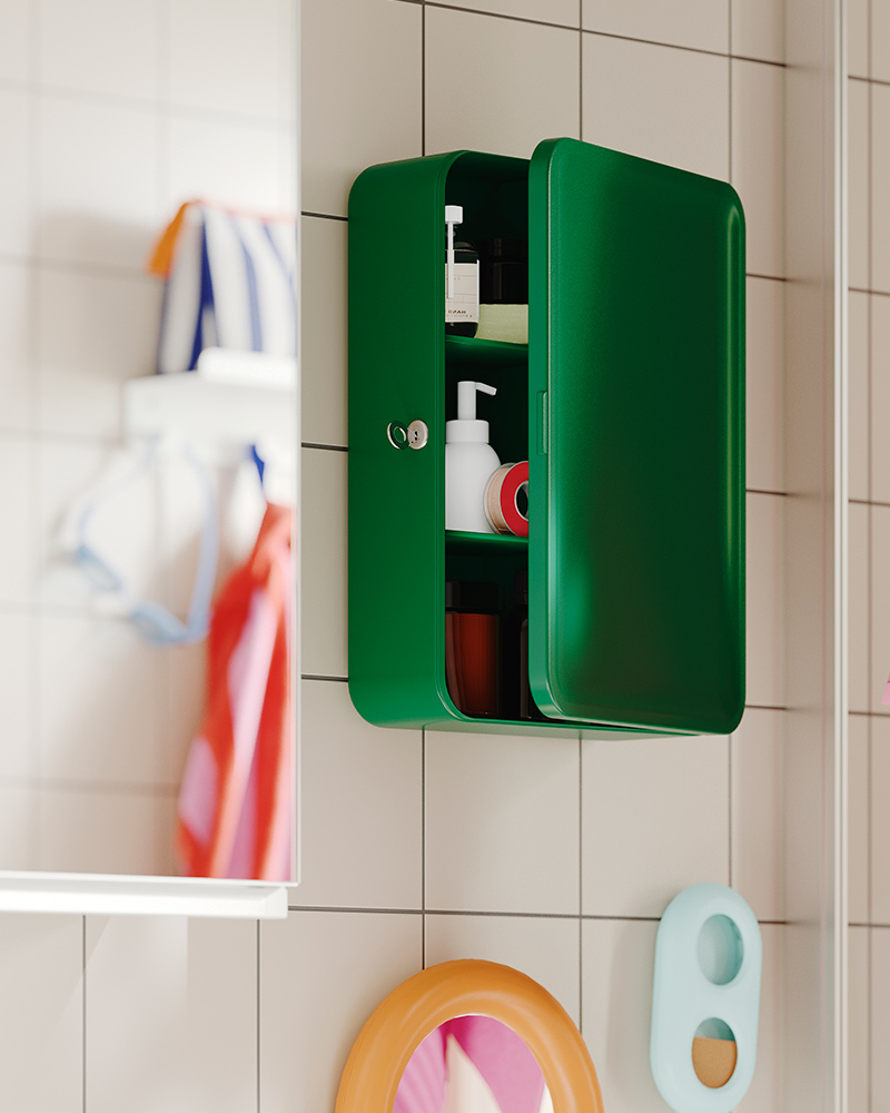 A green HUSBYÅN wall cabinet with door open, wallmounted in a tiled bathroom, shelves holding toiletries and a pink towel.