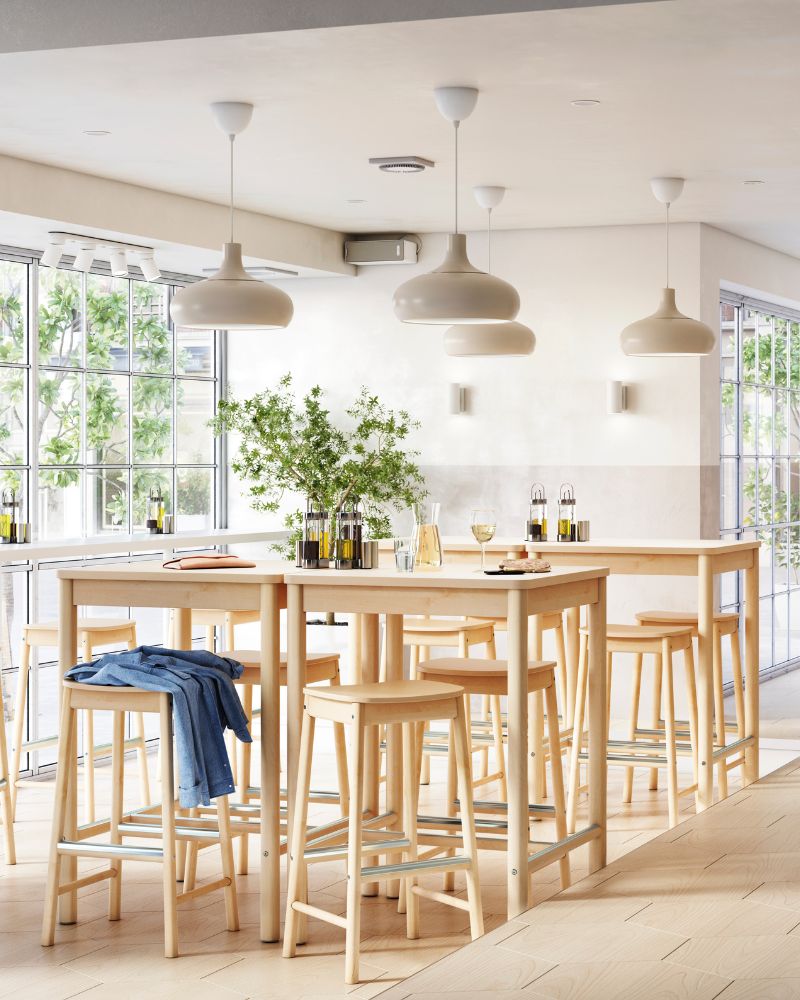 Bright restaurant bar area with RÖNNINGE bar table and stools, NYMÅNE lighting, SVALKA wine glass and KARAFF carafe