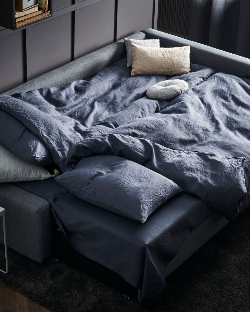 Sala moderna con sofá cama FRIHETEN, alfombra STOENSE, funda nórdica ÄNGSLILJA y cortinas LENDA.