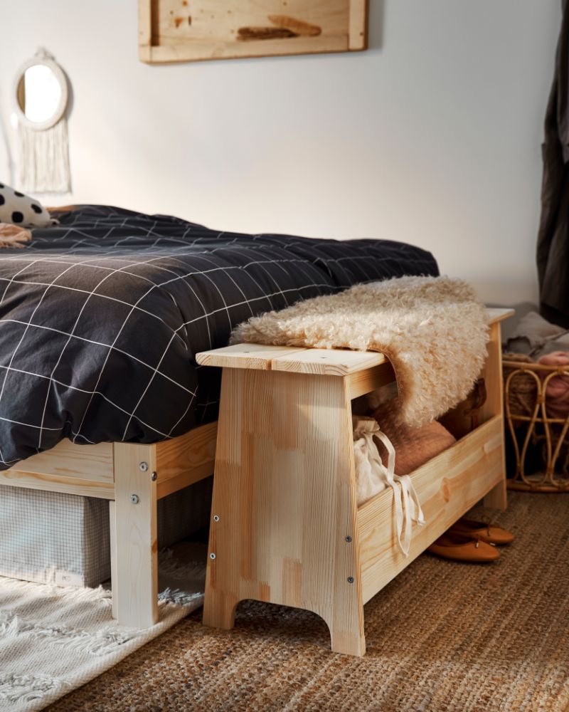 Cálido dormitorio con cama twin NEIDEN, taburete con almacenaje PERJOHAN, canasta SNIDAD, colcha VITKLÖVER y alfombra LOHALS.
