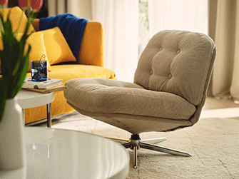 Sillón giratorio acolchado en color beige sobre una alfombra clara, junto a una mesa de centro blanca y un sofá amarillo brillante.