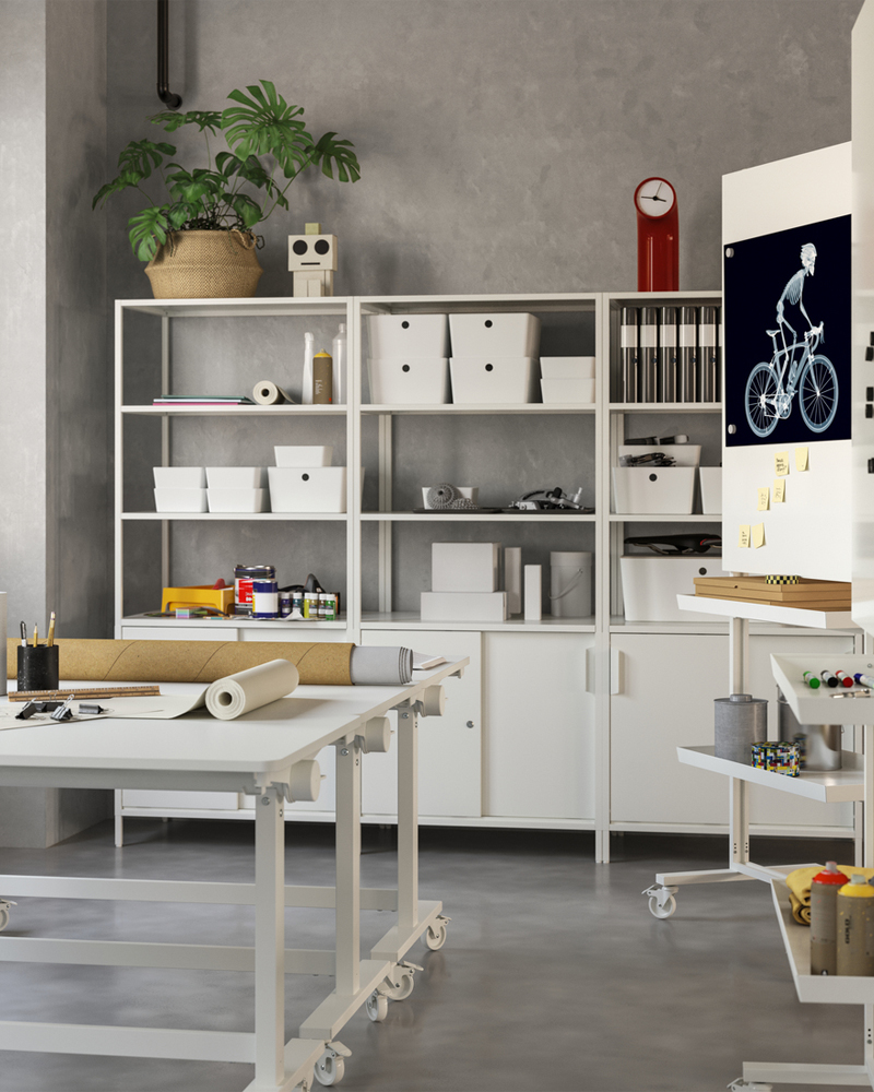 Creative workspace with two white tables on castors. Storage units with closed and open storage rest against the back wall.